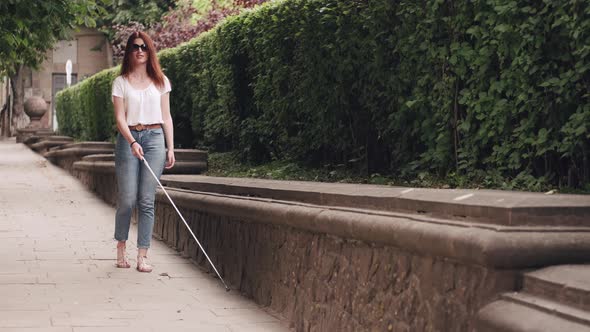 Young Blind Person with Long Cane Walking in a City