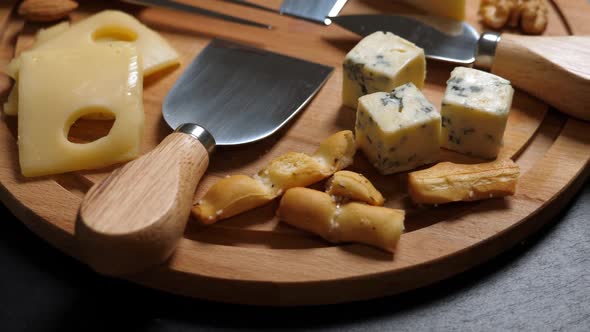 Sliced Cheesenuts Grape Honey and Knife on Wooden Platter