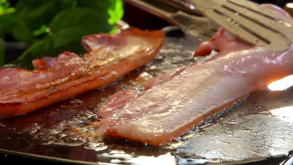 Cook Turns Bacon with Metal Tongs