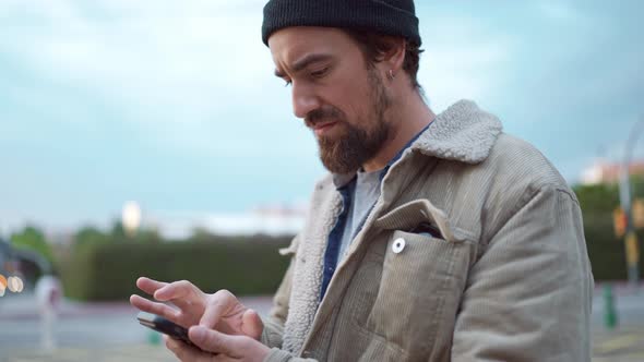 Meditative man wearing hat peering at the screen on mobile