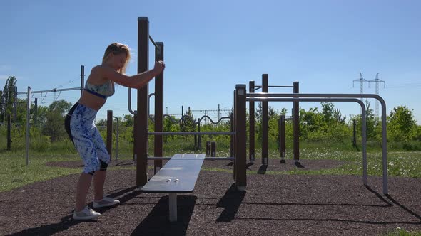 A Fit Beautiful Woman Jumps on and Off a Bench at an Outdoor Gym
