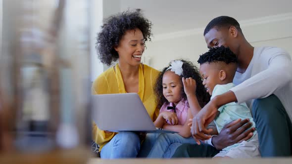 Front view of black family using laptop in living room at home 4k