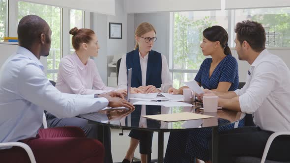 Mature Female Entrepreneur Explaining Business Strategy to Board of Directors in Conference Room