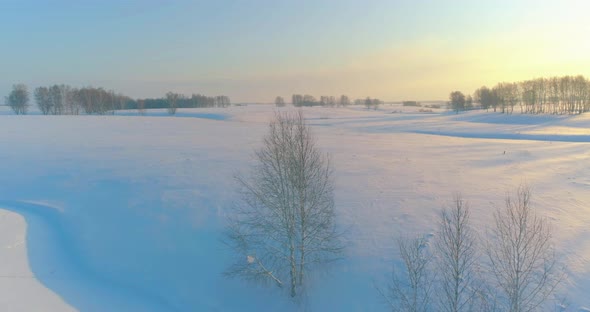 Aerial View of Cold Arctic Field Landscape Trees with Frost Snow Ice River and Sun Rays Over Horizon