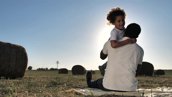 Cute Girl Hugging Dad Sitting on Blanket at Nature