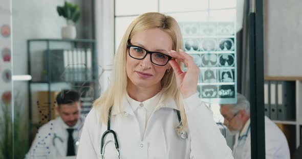 Female Doctor Taking off Glasses and Looking Into Camera with Satisfied Face
