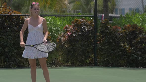 A young woman playing tennis with her boyfriend while on vacation.