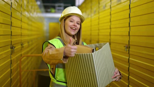 Medium Shot of Happy Young Woman Posing with Box Gesturing Thumb Up Smiling Looking at Camera