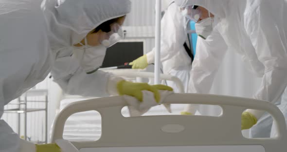 Team in Protective Suit and Mask Disinfecting Furniture in Hospital Room From Corona Virus