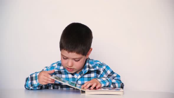 A Preschool Boy Reads a Book Closes It and Pushes It Away From Himself