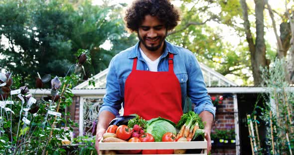 Gardener carrying crate of fresh vegetables