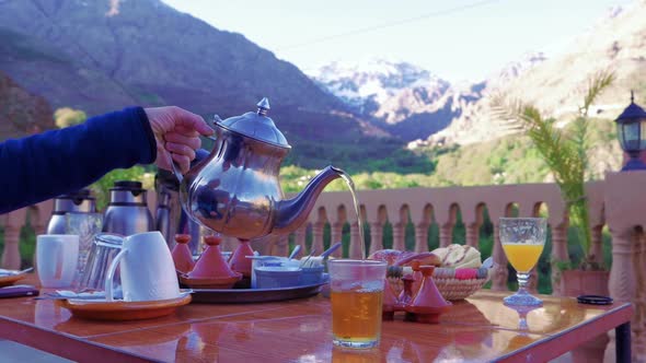 Pouring tea from silver teapot on rooftop terrace, Morocco, slow motion