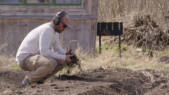 Man checks the soil on a farm, agriculture, wide shot slow motion