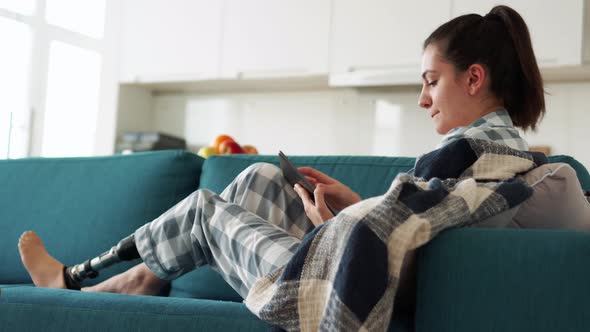 Happy woman with leg prosthesis texting by tablet