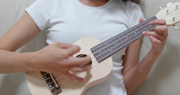 Woman play with ukulele at home