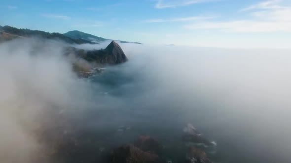 AERIAL: Pushing through a mist filled day towards a mountain on the Oregon coastline.