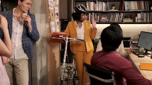 Female worker use the bicycle to go home, say goodbye to colleagues.