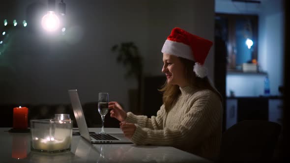 Woman in a Santa Hat Taking a Video Call on a Laptop with Friends