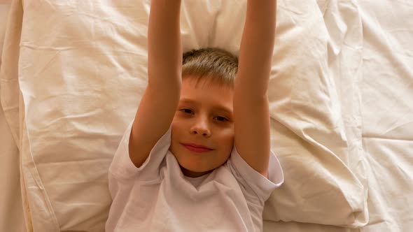 Morning awakening Caucasian boy 6-9 years old in bed.