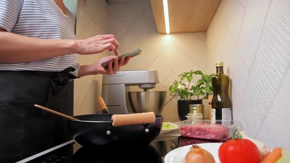 Woman Cooking Sauce Bolognese and Use Smartphone