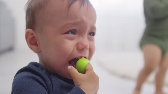 Upset Asian Toddler Crying and Twin Walking by