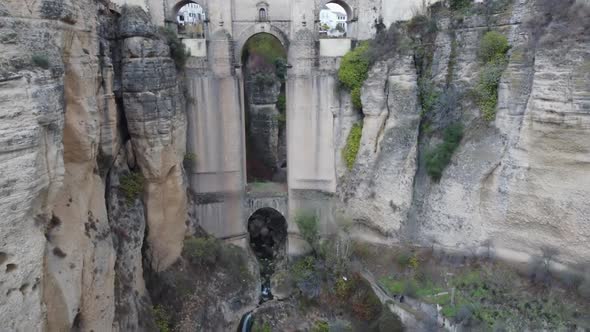 Aerial descends height of historic arch bridge over deep chasm, Spain