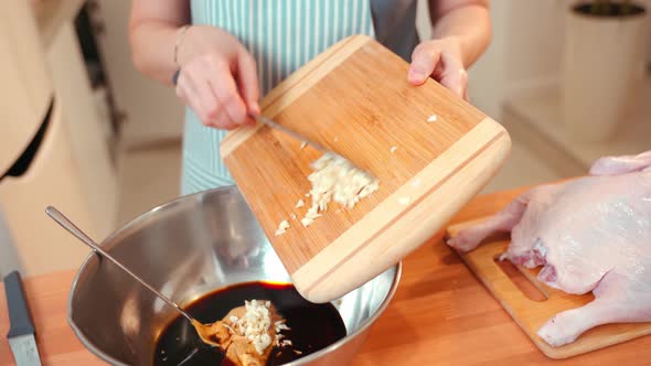 A Woman Adds Chopped Garlic to a Soy Marinade