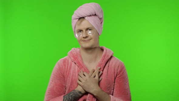 Portrait of Young Man in Bathrobe Looking in Mirror Wearing Eye Patches