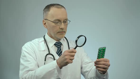 Doctor Looking at Pack of Pills Through Magnifying Glass, Counterfeit Medication