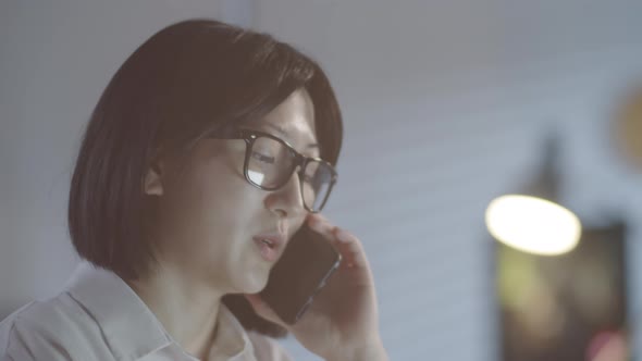 Woman Chatting on Phone while Working Overtime in Office