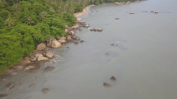 Tracking shot of rock and sandy beach at seashore.