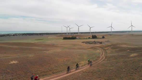 People Ride Bicycle To the Wind Turbine Farm