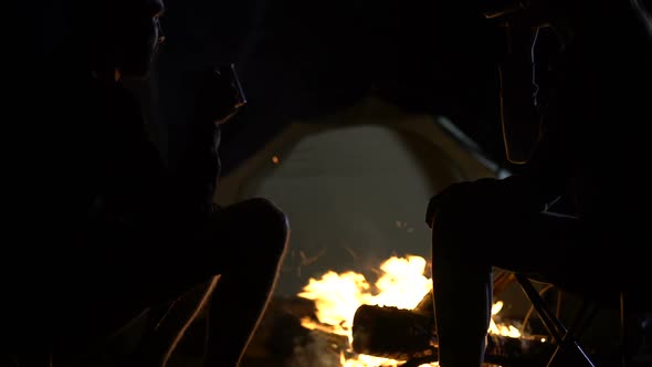Married Couple Clinking Cups and Drinking Alcohol Near Campfire, Anniversary