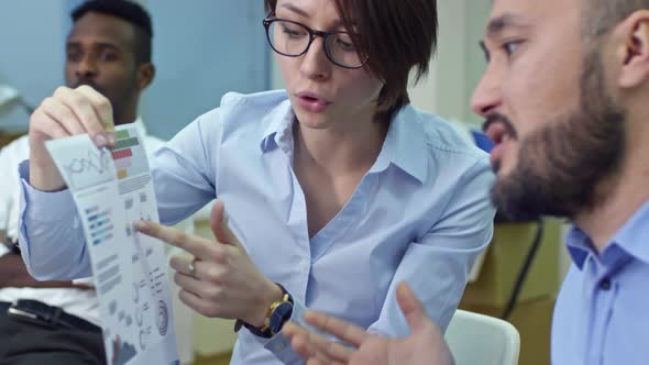 Woman Discussing Financial Document with Male Coworker in New Office