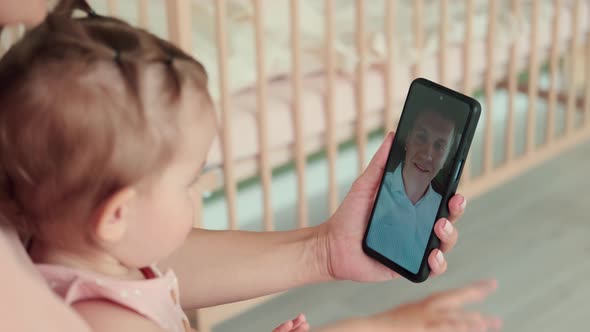 Mom and Child During an Online Call with Dad at Home