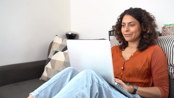 Smiling woman using laptop sitting on couch