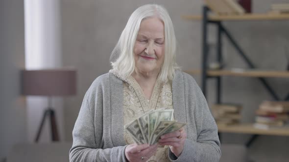 Wealthy Old Caucasian Woman Holding Cash Dollars As Fan Looking at Camera Smiling