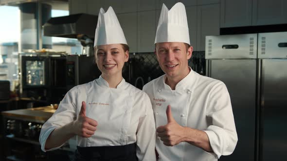 Professional kitchen portrait: Female and Male Chef give a thumbs up