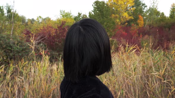 Sideways tracking shot of Japanese girl walking through autumn park