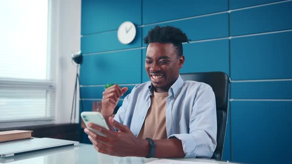 Overjoyed Young African American Man Rejoices Positive News in Mobile Phone