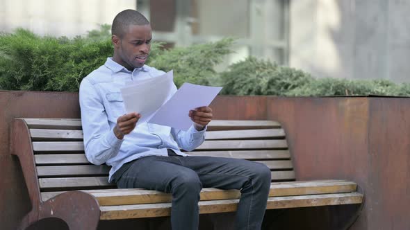 African Man Frustrated and Disappointed After Reading Documents Outdoor 