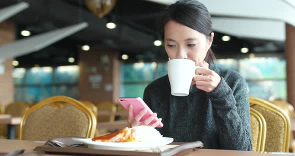 Busy woman having lunch in restaurant with using mobile phone