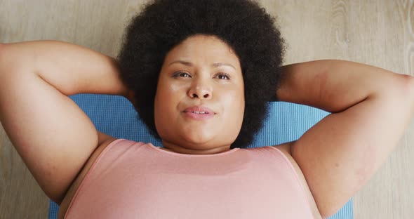 Video of plus size african american woman exercising at home