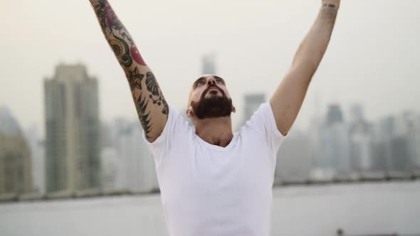 Man Spreads His Tattooed Arms Up As He Simultaneously Moves His Body