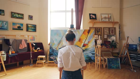 Blond Girl Artist Is Painting Marine Landscape Working in Light Workshop