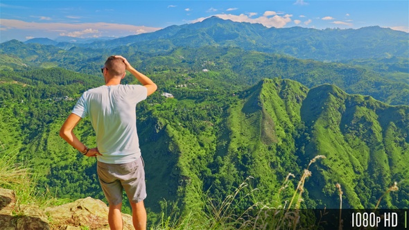 Man Standing on top of a mountain looking at beautiful mountains view in Ella, Sri Lanka