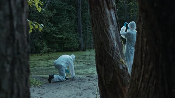 People Wearing Protective White Suits Taking Soil and Water Samples for Testing