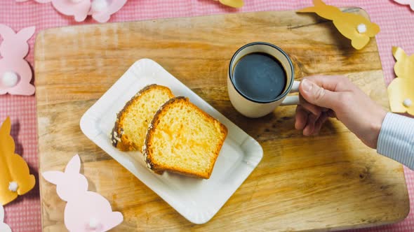 The Woman Puts a Cup of Coffee on the Table Where There is a Chocolate Cake