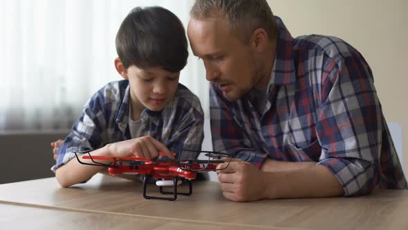 Curious Father and Little Son Examining New Quadrocopter Model at Home, Fun