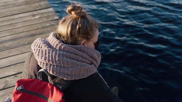 Girl Sits on the Pier By the Lake and Rests